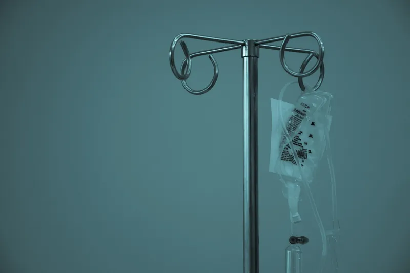 Bolsa de suero intravenoso (IV) colgada de un soporte metálico.