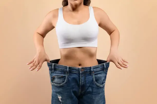 Mujer mostrando pérdida de peso con jeans holgados
