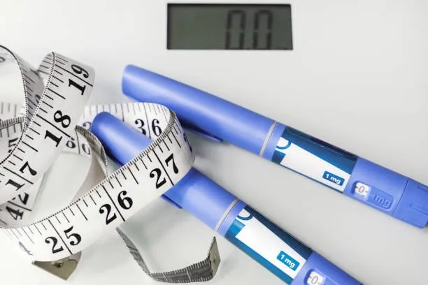 Concepto de pérdida de peso con plumas de inyección etiquetadas 1 mg, cinta métrica y báscula digital que marca cero
