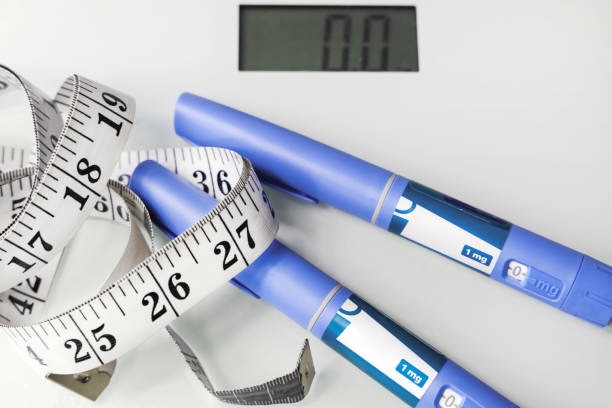 Weight loss concept with injection pens labeled 1 mg, measuring tape, and digital scale showing zero
