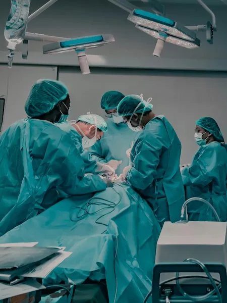 Profesionales de la salud con uniforme quirúrgico realizan una cirugía en un quirófano hospitalario.