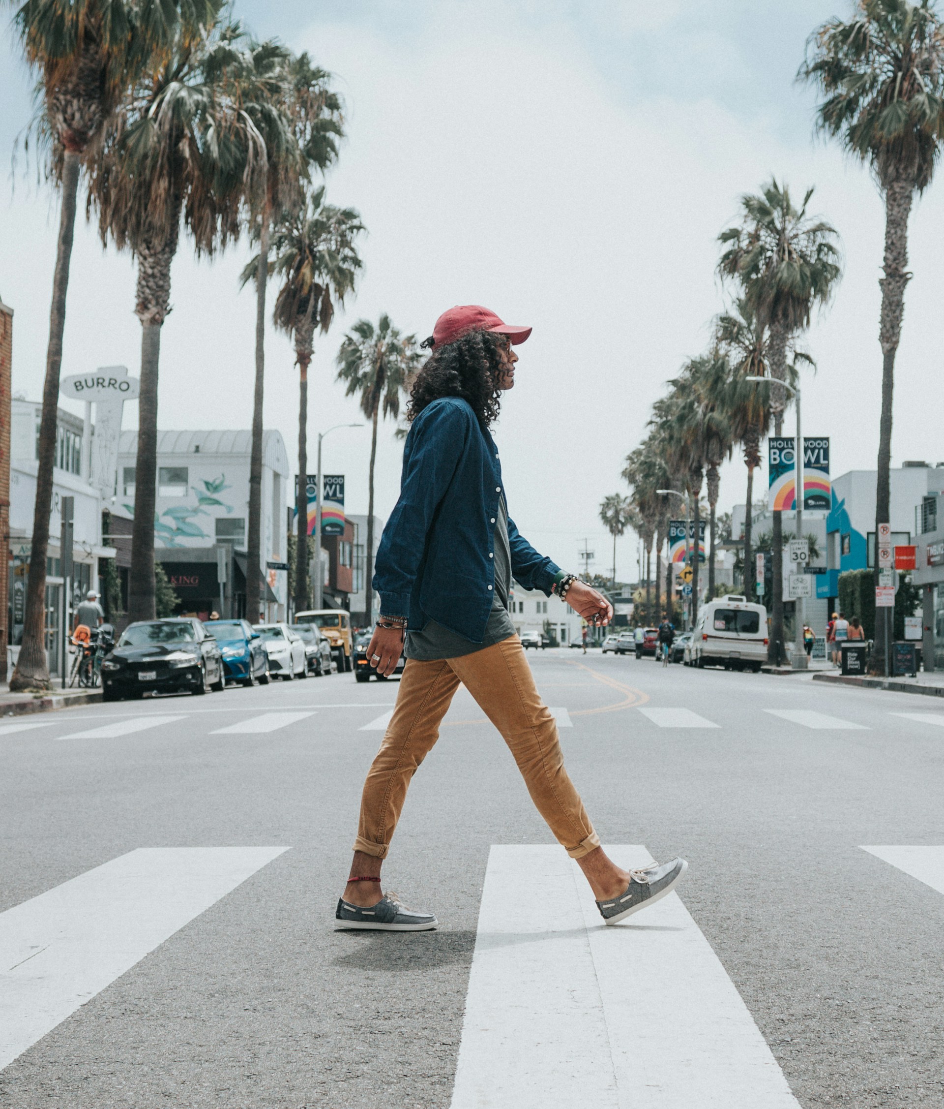 Person wearing red cap crossing street