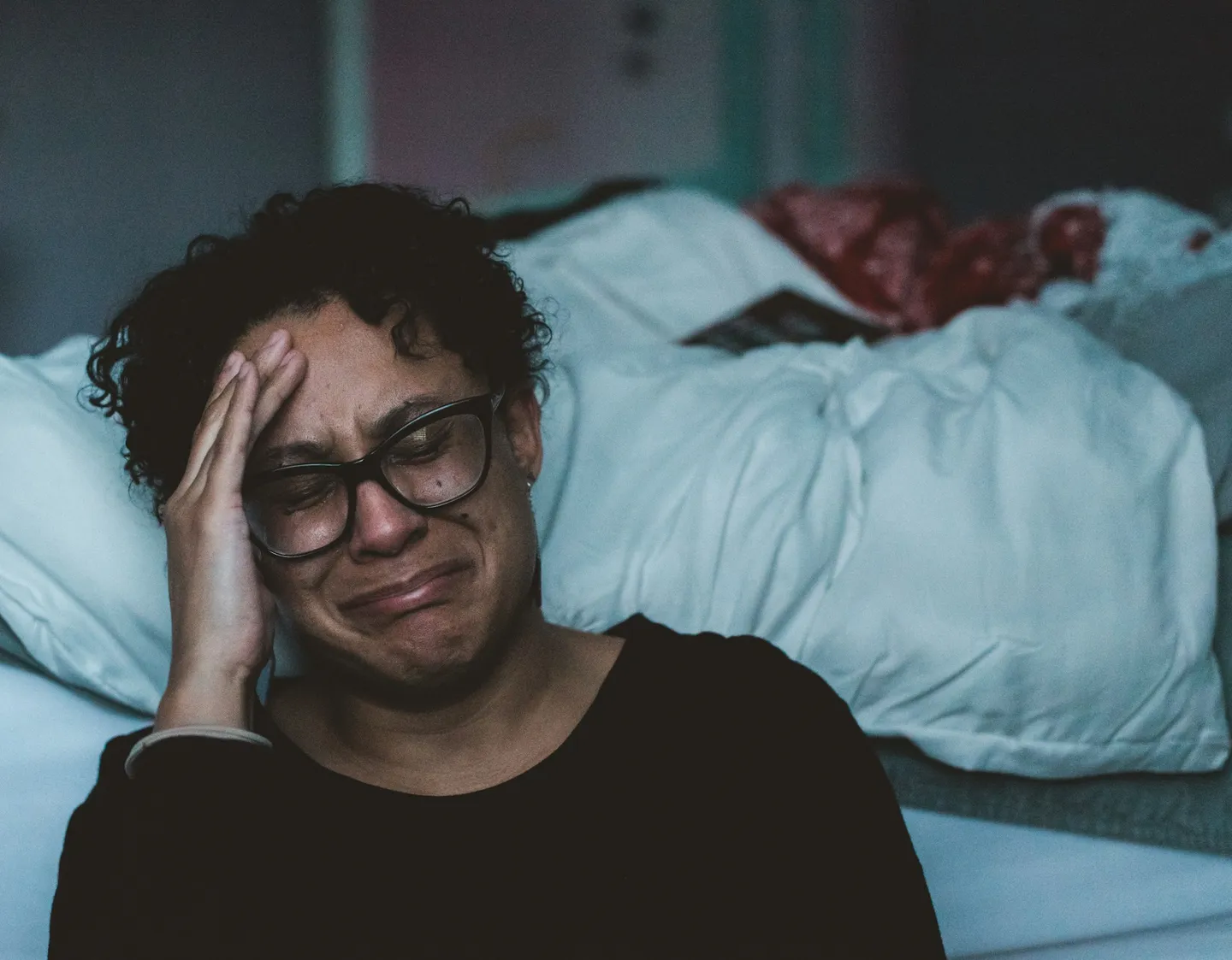 A woman crying beside a bed